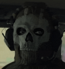 a man wearing a skull mask and headphones is looking at the camera .