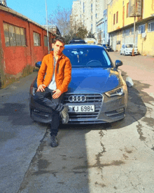 a man kneeling in front of an audi with a license plate that says kj 6984