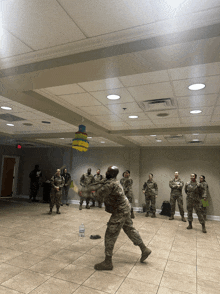 a group of soldiers are playing a game in a room with a pinata hanging from the ceiling