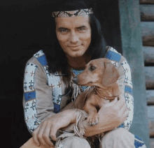 a man in a native american outfit holds a small dog