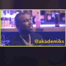 a man sitting at a bar with the word akademiks on the bottom right