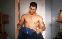 a shirtless man is taking off a blue shirt in a room .