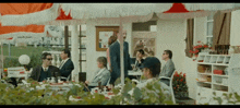 a group of people sitting at tables under an umbrella with a sign on the wall that says ' a ' on it