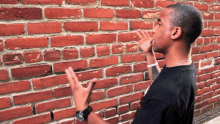 a man standing in front of a brick wall