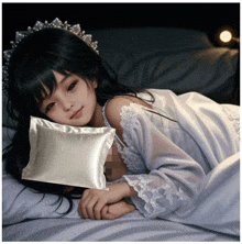 a little girl laying on a bed with a white pillow