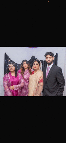 a group of people posing for a picture including a man in a suit and two women in dresses