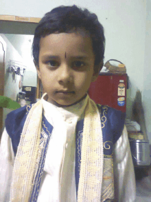 a young boy wearing a white shirt and a blue vest has a sticker on his jacket that says ' a ' on it