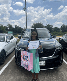 a girl in front of a car holding a certificate and a bag that says fab you jealous