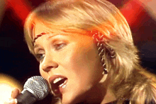 a close up of a woman singing into a microphone with the number 25 written on the bottom