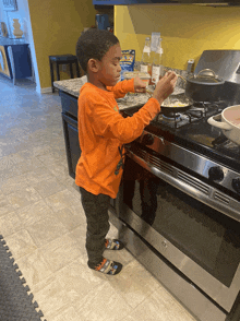 a young boy in a hot wheels shirt prepares food on the stove