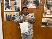 a boy is holding a white bag in front of a door with pictures on it