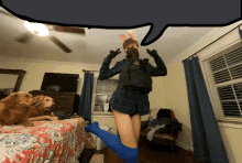 a woman wearing bunny ears and blue knee high socks stands in a bedroom with two dogs