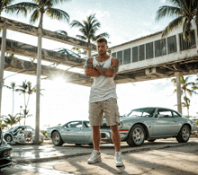 a man with his arms crossed stands in front of a row of cars