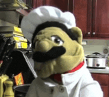 a stuffed animal with a chef 's hat and mustache is in a kitchen