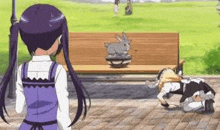 a girl in a purple dress is standing next to a bench with a bunny on it .