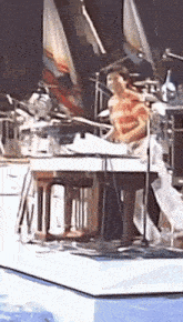 a man is playing a piano on a stage in front of a microphone