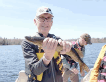 a man on a boat holds a fish in his hands