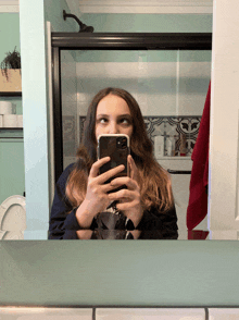 a woman taking a picture of herself in the bathroom mirror