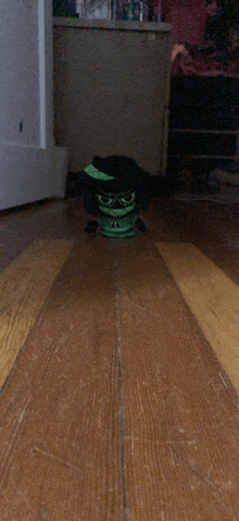 a toy with a hat and glasses sits on a wooden floor