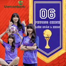 a girl holding a soccer ball in front of a banner that says vietcombank on it