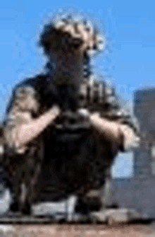 a blurry picture of a soldier sitting on top of a vehicle holding a gun .