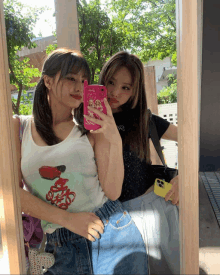 two girls are taking a selfie in front of a mirror with one girl holding a pink case that says ' disney '