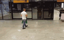 a man in a white shirt is walking in front of a building with a yellow sign that says aeroporto