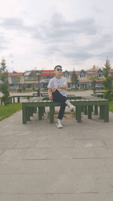 a man wearing sunglasses sits on a bench