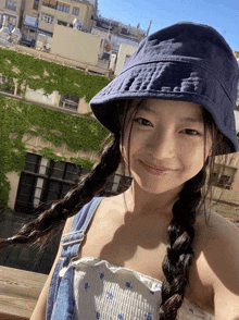 a girl wearing a blue hat and overalls smiles