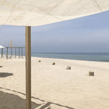 a beach with a white umbrella and a yellow flag in the background