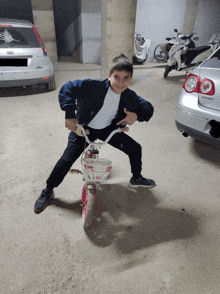 a young boy riding a pink bicycle in a parking lot