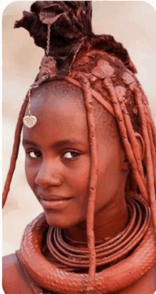 a woman with red dreadlocks and a heart shaped pendant on her forehead