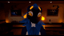 a blue furry animal with yellow eyes is in a room