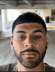 a man with a beard and earrings is taking a selfie