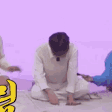 a man is sitting on the floor wearing a large purple hat .