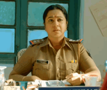 a woman in a police uniform sits at a desk with a name tag that says ' s. krishna '