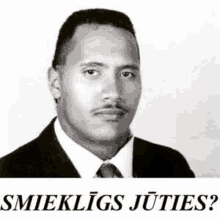 a black and white photo of a man in a suit and tie with the words smiekligs juties written below him .