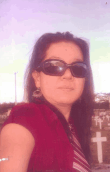 a woman wearing sunglasses is standing in front of a cemetery with crosses