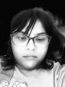 a black and white photo of a girl wearing glasses and a shirt with simpson faces on it