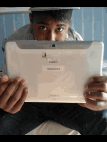 a boy is holding a white samsung tablet