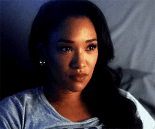 a close up of a woman 's face wearing a gray shirt and earrings .