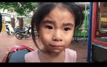 a little girl is crying and looking at the camera in a park .