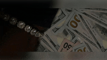 a stack of twenty dollar bills next to a bracelet