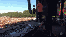 a man stands on a stage in front of a crowd at a festival with a sign that says ' chicago ' on it