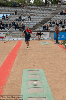 a man is throwing a ball in front of a vichy sign