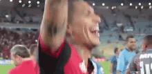 a man in a red shirt is raising his hands in the air .