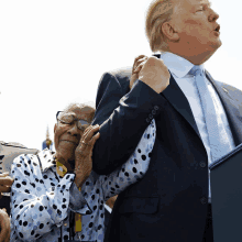 a man in a suit and tie is holding a woman in a polka dot shirt