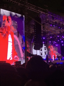 a man in a red hat is standing on a stage in front of a large screen