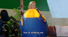 a woman sitting in a bean bag chair holding a microphone and saying you 're shitting me