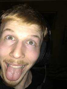 a man wearing headphones sticks out his tongue